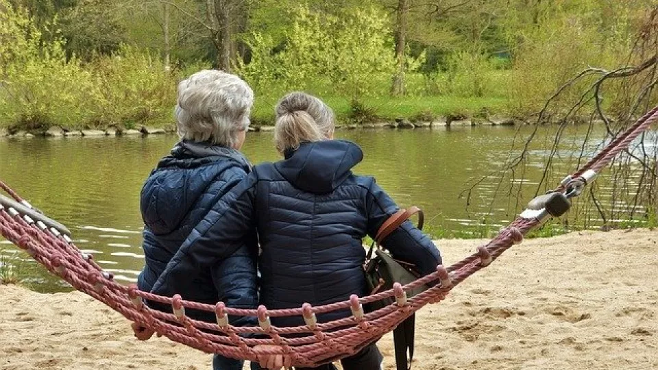 Foto. Två kvinnor sitter vid en sjö