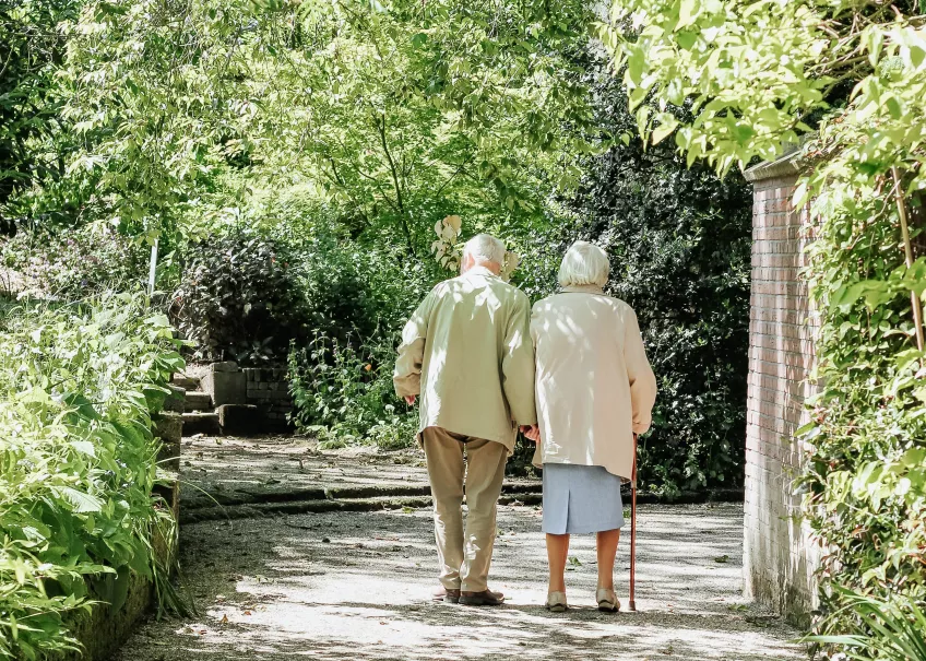Äldre par promenerar i skogen